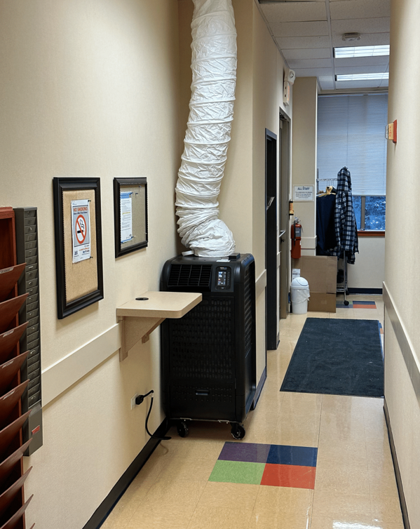 A hallway with a wall mounted air conditioner and a table.